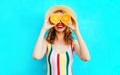 Summer portrait happy smiling woman holding in her hands two slices of orange fruit hiding her eyes in straw hat on colorful blue Royalty Free Stock Photo