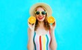 Summer portrait happy smiling woman holding in her hands two slices of orange fruit in straw hat on colorful blue Royalty Free Stock Photo