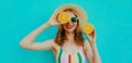 Summer portrait happy smiling woman holding in her hands two slices of orange fruit in straw hat on a colorful blue background Royalty Free Stock Photo