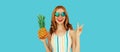 Summer portrait of happy smiling woman with pineapple wearing sunglasses posing on blue background