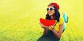 Summer portrait of happy smiling young woman eating fresh juicy slice of watermelon on the grass in the summer park Royalty Free Stock Photo