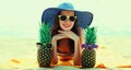 Summer portrait of happy smiling young woman lying on the beach with funny pineapple wearing straw hat Royalty Free Stock Photo