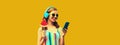 Summer portrait of happy smiling young woman model in headphones listening to music on smartphone with juicy lollipop or ice cream Royalty Free Stock Photo