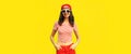Summer portrait of happy smiling young woman model wearing baseball cap, red shorts on yellow background Royalty Free Stock Photo