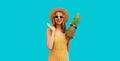 Summer portrait of happy smiling young woman with pineapple wearing sunglasses, straw hat posing on blue background Royalty Free Stock Photo