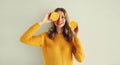 Summer portrait of happy smiling young woman with slices of fresh orange fruits on gray background