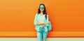 Summer portrait of happy smiling young woman wearing straw hat, backpack and shirt on orange background, blank copy space for Royalty Free Stock Photo