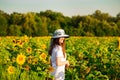 Summer portrait of happy young woman in hat with long hair in sunflower field Royalty Free Stock Photo