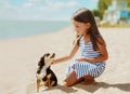 Portrait of little girl child with dog sitting together on sand beach Royalty Free Stock Photo