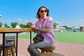 Summer portrait of mature woman with smartphone, female resting in outdoor cafe