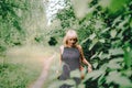Summer portrait of scared mature adult blonde woman near the trees on sunny day in the park. Royalty Free Stock Photo