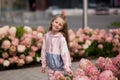 Summer portrait of a smiling girl. Little beautiful girl blonde. Pink flowers on flowerbed.