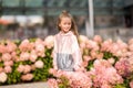 Summer portrait of a smiling girl. Little beautiful girl blonde. Pink flowers on flowerbed.