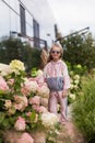 Summer portrait of a smiling girl. Little beautiful girl blonde. Pink flowers on flowerbed.