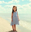 Summer portrait smiling little girl child wearing striped dress on a beach on a sea background Royalty Free Stock Photo