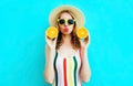 Summer portrait woman holding in her hands two slices of orange fruit in straw hat on colorful blue Royalty Free Stock Photo