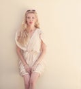 Summer portrait of young beautiful blond woman in white dress posing near the wall and have fun. Toned in warm colors Royalty Free Stock Photo