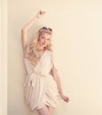 Summer portrait of young beautiful blond woman in white dress posing near the wall and have fun. Toned in warm colors Royalty Free Stock Photo