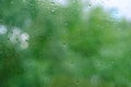 summer rain outside window, green foliage of trees out focus, texture glass of background with water drops, place for text, Royalty Free Stock Photo