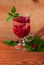 Summer raspberry cold tea in a glass on wooden background. Healthy fruit cocktail. Tasty red juice fresh green leaves Royalty Free Stock Photo