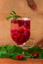 Summer raspberry cold tea in a glass on wooden background. Healthy fruit cocktail. Tasty red juice fresh green leaves Royalty Free Stock Photo