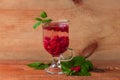 Summer raspberry cold tea in a glass on wooden background. Healthy fruit cocktail. Tasty red juice fresh green leaves Royalty Free Stock Photo
