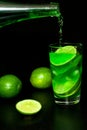 Glass of cold drink with ice and fresh ripe slice green limes on black