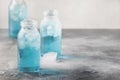 Summer refreshing cold drink, isotonic blue water in bottles, gray table background, selective focus Royalty Free Stock Photo