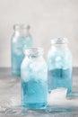 Summer refreshing cold drink, isotonic blue water in bottles, gray table background, selective focus Royalty Free Stock Photo
