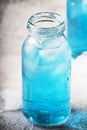 Summer refreshing cold drink, isotonic blue water in bottles, gray table background, selective focus Royalty Free Stock Photo