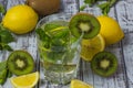 Summer refreshing drink in a glass with straw close-up. Cold sweet and sour lemonade with cubes of lemon, kiwi, mint and ice Royalty Free Stock Photo