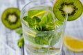 Summer refreshing drink in a glass with straw close-up. Cold sweet and sour lemonade with cubes of lemon, kiwi, mint and ice Royalty Free Stock Photo