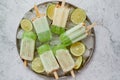 Summer refreshing homemade lime popsicles with chipped ice over stone background Royalty Free Stock Photo