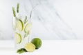 Summer refreshing organic citrus beverage with ice, lime slice, green rosemary twig, silver straw, ingredients in minimal soft. Royalty Free Stock Photo