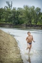 In the summer on the river the boy runs along the shore. Royalty Free Stock Photo