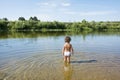 In the summer on the river a little girl stands in the water. Royalty Free Stock Photo
