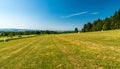 Summer rolling landscape with meadows, haystacks, forests and blue sky