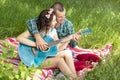 Summer romantic picnic. guy shows the girl how to play the guitar. couple sitting on the grass Royalty Free Stock Photo