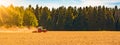Summer rural / agriculture harvest background banner panorama: old tractor milling straw grain barley wheat field, with blown dust