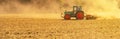 Summer rural / agriculture harvest background banner panorama: old tractor milling straw grain barley wheat field, with blown dust