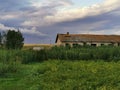 Rural landscape with cloudy sky at sunset and abandoned house