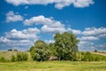 Summer rural landscape with lonely abandoned hut among the trees. Blue sky with clouds background