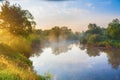 Summer rural landscape with river, forest and fog