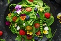 Summer salad with edible flowers, spinach, blueberries, raspberry, sweet peas, cherry tomatos and feta cheese Royalty Free Stock Photo