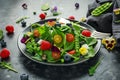 Summer salad with edible flowers, spinach, blueberries, raspberry, sweet peas, cherry tomatos and feta cheese Royalty Free Stock Photo