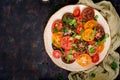 Summer salad of tomatoes of different colors with green herbs and pepper. Royalty Free Stock Photo