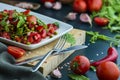 summer salad, tomatoes, green peas, arugula, onion, olive oil, garlic, hot pepper fork knife bamboo cutting board pastel green Royalty Free Stock Photo