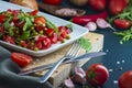 summer salad, tomatoes, green peas, arugula, onion, olive oil, garlic, hot pepper fork knife bamboo cutting board pastel green Royalty Free Stock Photo