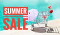 Summer sale banner with Empty shopping cart with paper umbrella over blurred blue water background Royalty Free Stock Photo