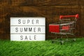 Summer Sale text in light box and mini trolley shopping cart on wooden background Royalty Free Stock Photo